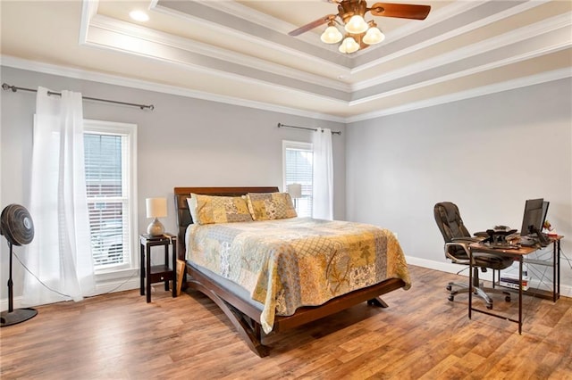 bedroom featuring hardwood / wood-style floors, ceiling fan, ornamental molding, and a tray ceiling