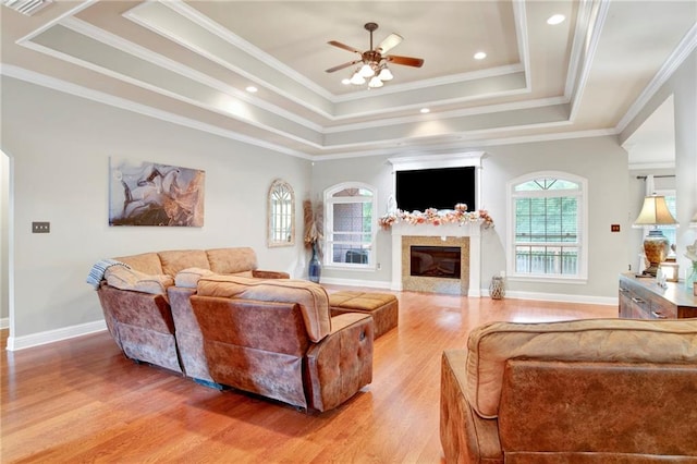 living room featuring a tray ceiling, hardwood / wood-style floors, ceiling fan, and crown molding