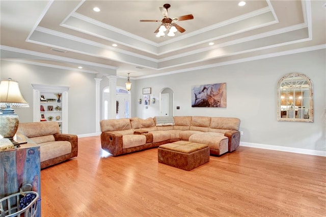 living room featuring ceiling fan, a tray ceiling, hardwood / wood-style floors, and ornate columns