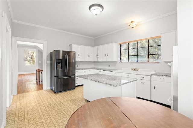 kitchen featuring white cabinets, stainless steel fridge with ice dispenser, ornamental molding, and a wealth of natural light