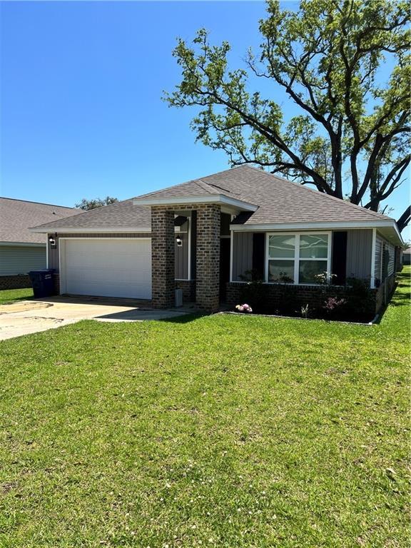 6157 Stream Bank Dr, Mobile, AL 36582 - single story home with a shingled roof, a garage, concrete driveway, brick siding, and a front lawn