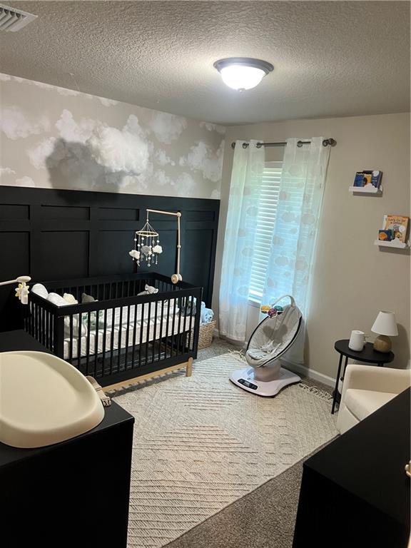 6157 Stream Bank Dr, Mobile, AL 36582 - bedroom featuring wallpapered walls, a crib, a textured ceiling, a wainscoted wall, and visible vents