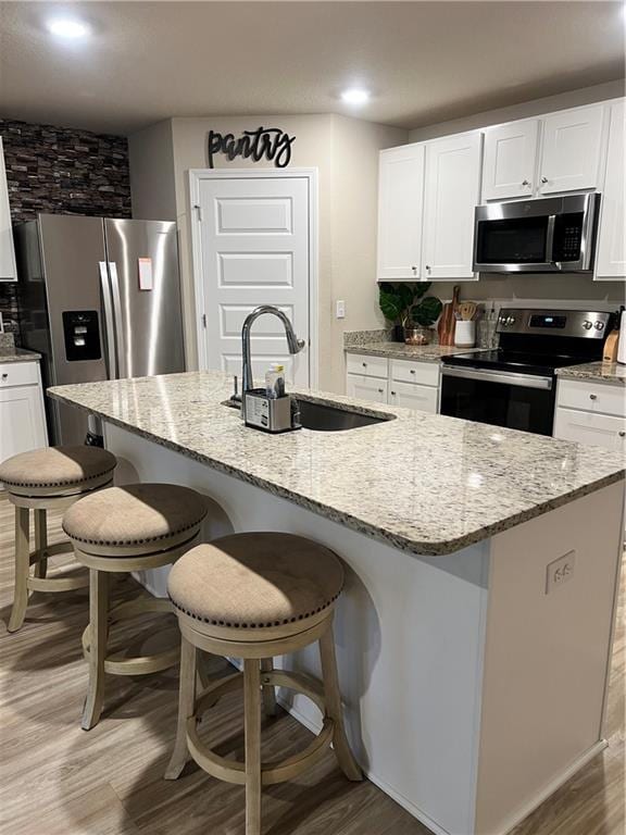 6157 Stream Bank Dr, Mobile, AL 36582 - kitchen featuring stainless steel appliances, light wood-type flooring, a sink, and light stone counters