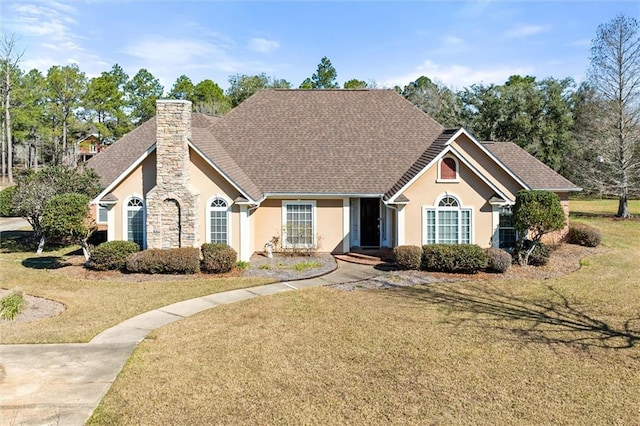 view of front of property with a shingled roof, a chimney, a front lawn, and stucco siding