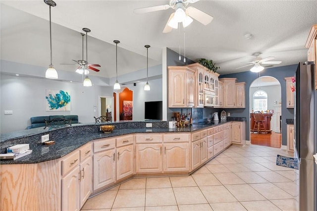 kitchen with freestanding refrigerator, arched walkways, open floor plan, and light brown cabinetry