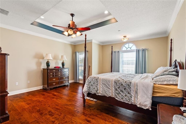 bedroom featuring visible vents, a tray ceiling, wood finished floors, and ornamental molding