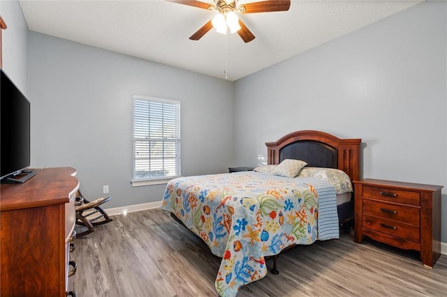 bedroom with ceiling fan, baseboards, and wood finished floors