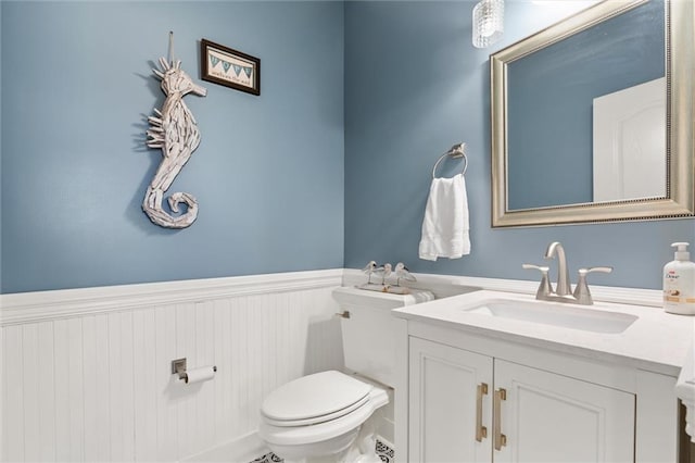 bathroom featuring a wainscoted wall, vanity, and toilet