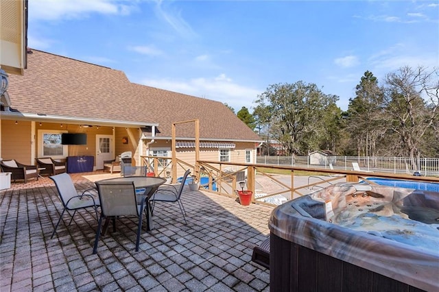 view of patio / terrace featuring a fenced in pool, outdoor dining space, fence, and a hot tub