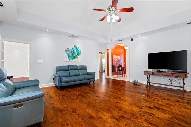 living area featuring baseboards, wood-type flooring, arched walkways, and a ceiling fan