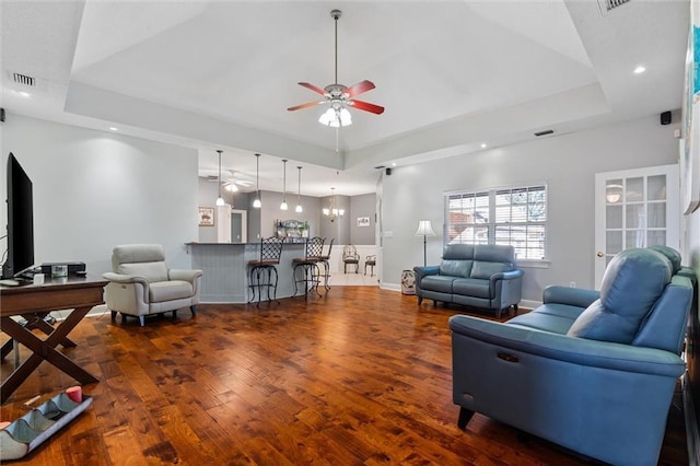 living room featuring a raised ceiling, visible vents, ceiling fan, wood finished floors, and baseboards