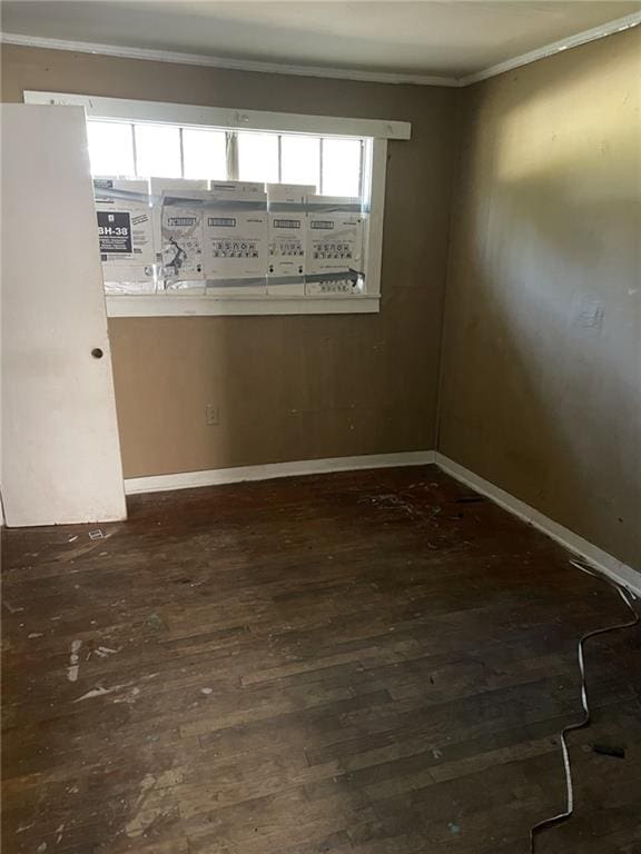 empty room with dark hardwood / wood-style floors and crown molding