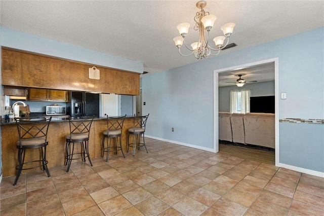 3660 Ching Dairy Rd, Mobile, AL 36618 - kitchen with black refrigerator with ice dispenser, stainless steel microwave, dark countertops, brown cabinetry, and a peninsula