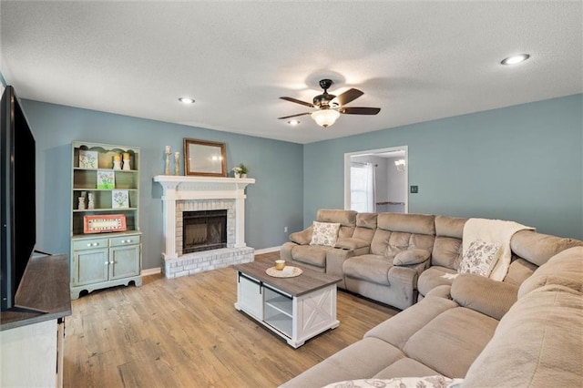 3660 Ching Dairy Rd, Mobile, AL 36618 - living room featuring a brick fireplace, light wood-type flooring, a ceiling fan, recessed lighting, and a textured ceiling