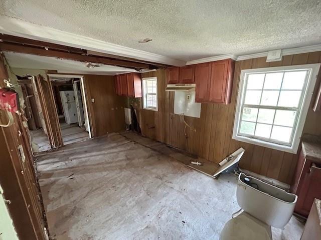 kitchen featuring wooden walls, brown cabinetry, and a textured ceiling