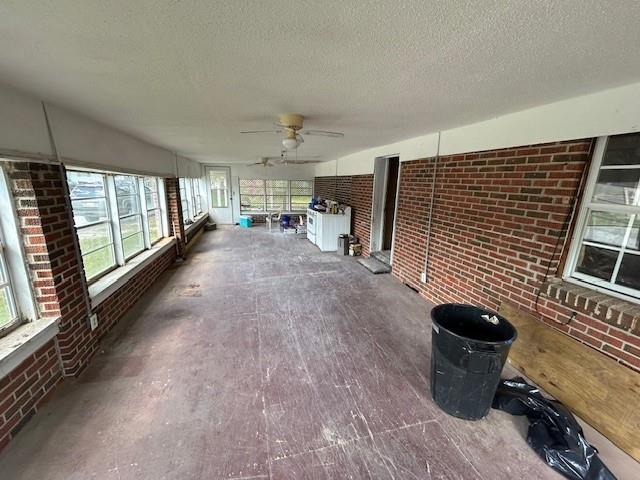 unfurnished sunroom featuring a ceiling fan