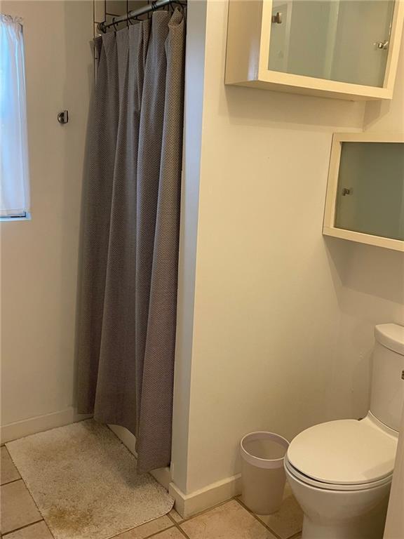 bathroom featuring tile patterned floors, a shower with curtain, and toilet