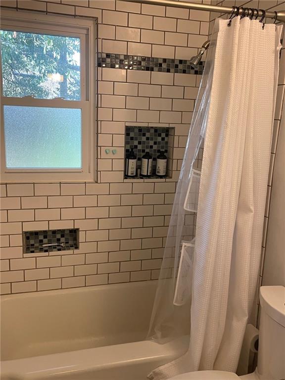 bathroom featuring toilet and shower / bath combo