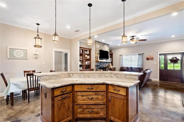 kitchen featuring ceiling fan, a center island, decorative light fixtures, a fireplace, and ornamental molding