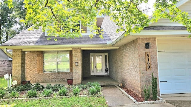 doorway to property featuring brick siding, a shingled roof, a garage, and a porch