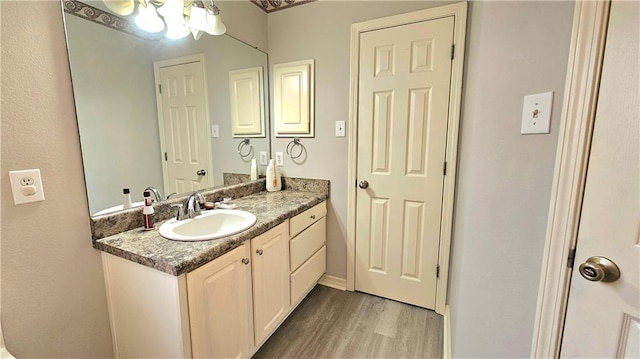 bathroom featuring a notable chandelier, wood finished floors, and vanity