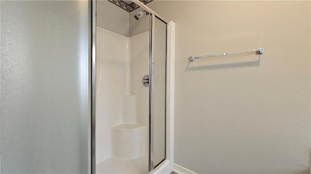 full bath with baseboards and a shower stall