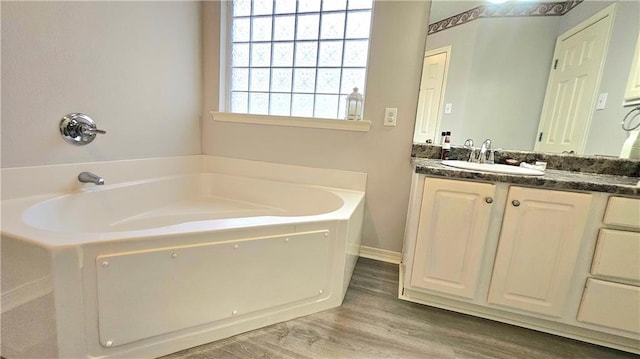 full bath featuring wood finished floors, a garden tub, and vanity