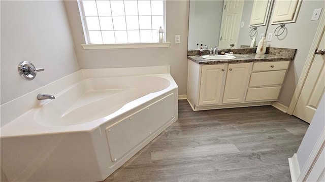 full bath featuring a garden tub, wood finished floors, and vanity