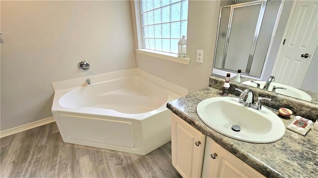 bathroom with vanity, baseboards, wood finished floors, a garden tub, and a stall shower