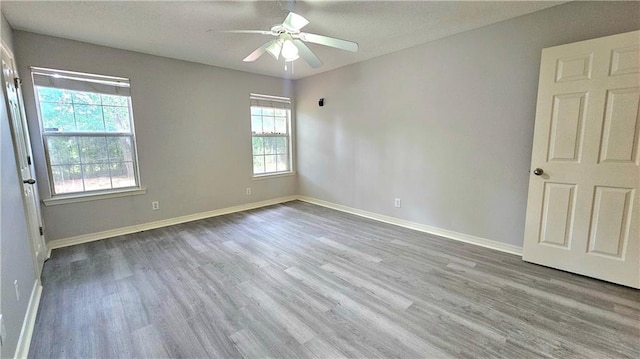 spare room with baseboards, ceiling fan, and wood finished floors