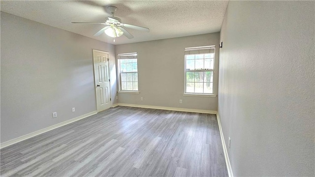 unfurnished room featuring baseboards, a ceiling fan, a textured ceiling, and wood finished floors