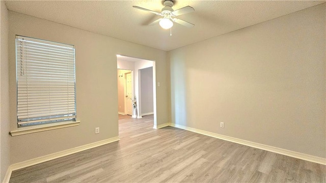 empty room featuring a ceiling fan, baseboards, wood finished floors, and a textured ceiling