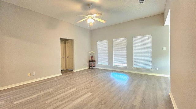 empty room with a ceiling fan, baseboards, visible vents, and wood finished floors