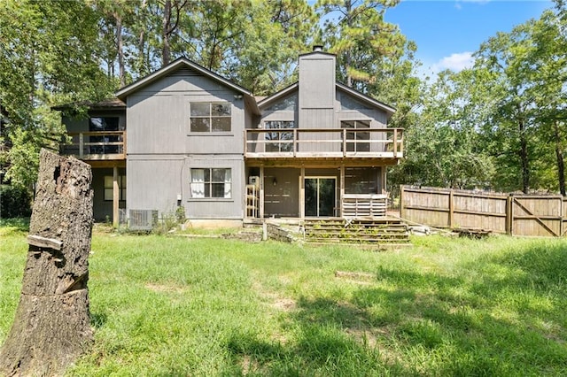 rear view of property featuring a sunroom, a lawn, a wooden deck, and cooling unit