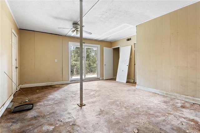 unfurnished bedroom featuring a textured ceiling, ceiling fan, wooden walls, and concrete flooring