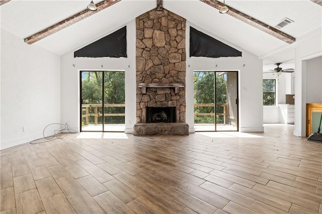 unfurnished living room with a fireplace, high vaulted ceiling, beam ceiling, and a wealth of natural light