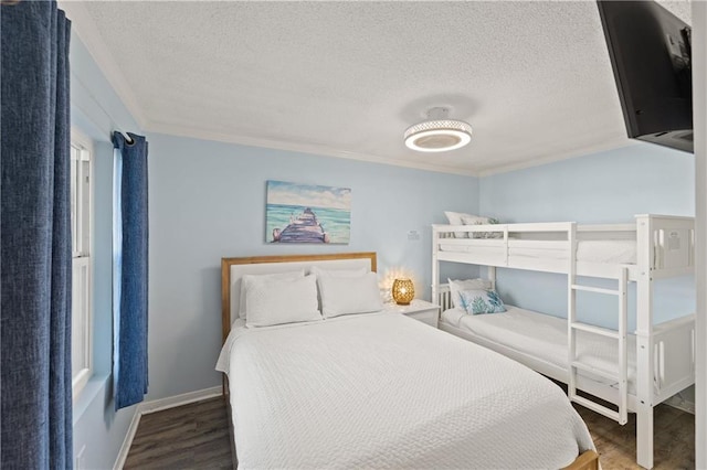 bedroom with dark wood-type flooring, a textured ceiling, and ornamental molding