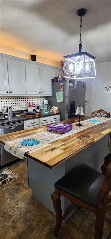 kitchen with wood counters, white cabinetry, stainless steel fridge, and decorative light fixtures