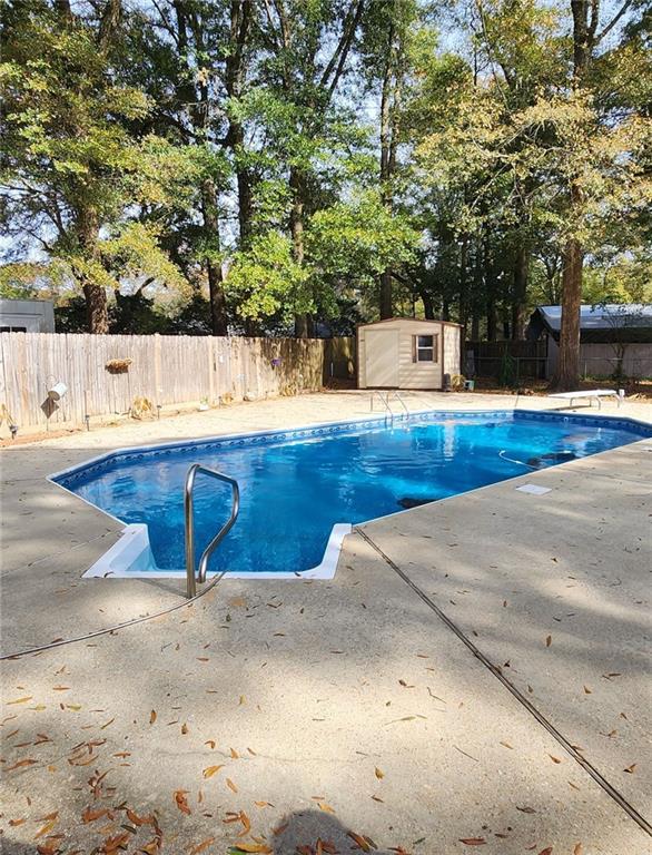 view of swimming pool with a storage shed and a diving board