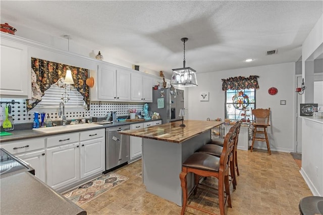 kitchen with sink, wooden counters, appliances with stainless steel finishes, a center island, and white cabinets