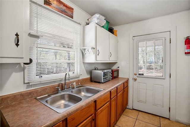 kitchen with a toaster, a healthy amount of sunlight, a sink, and light tile patterned floors