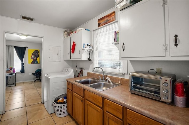 kitchen featuring a toaster, light tile patterned floors, visible vents, a sink, and separate washer and dryer