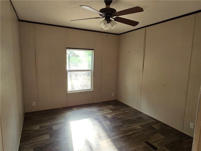 spare room featuring ceiling fan, dark hardwood / wood-style floors, and crown molding