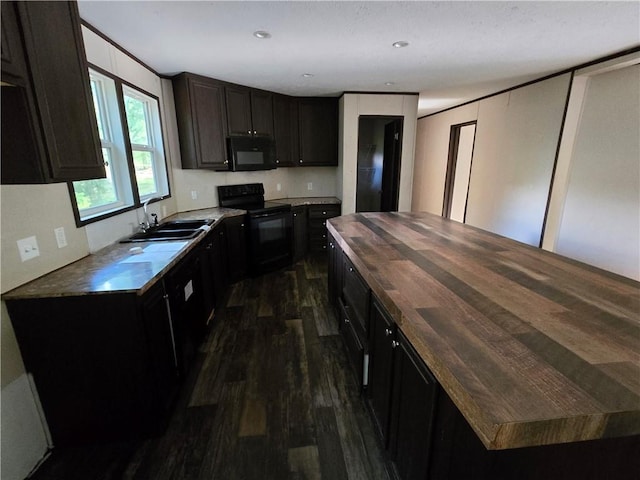 kitchen featuring butcher block counters, dark hardwood / wood-style floors, dark brown cabinets, black appliances, and sink