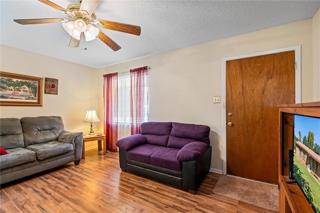 living room featuring a textured ceiling, light wood-type flooring, and ceiling fan