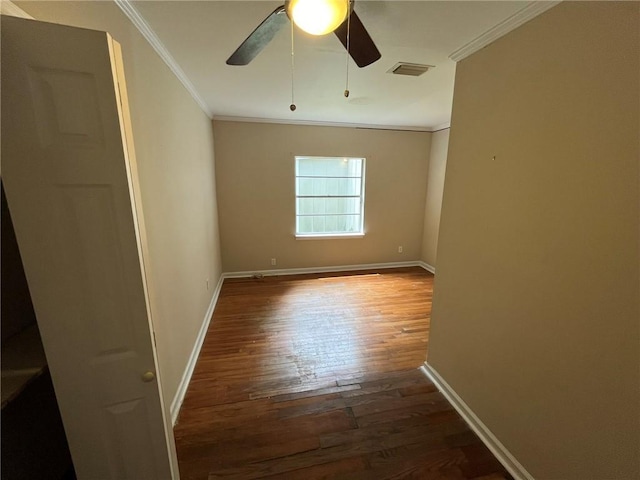 empty room with visible vents, crown molding, baseboards, and wood finished floors