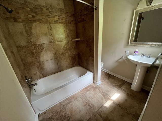 bathroom featuring tiled shower / bath, toilet, and tile patterned flooring