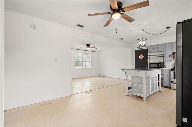 kitchen with range with electric stovetop, a breakfast bar area, ceiling fan, and a kitchen island