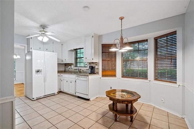 kitchen featuring ceiling fan with notable chandelier, backsplash, white appliances, white cabinets, and light tile patterned floors