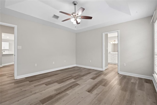 4625 Pine Blvd, Orange Beach, AL 36561 - unfurnished bedroom featuring wood finished floors, baseboards, a tray ceiling, ensuite bathroom, and a ceiling fan